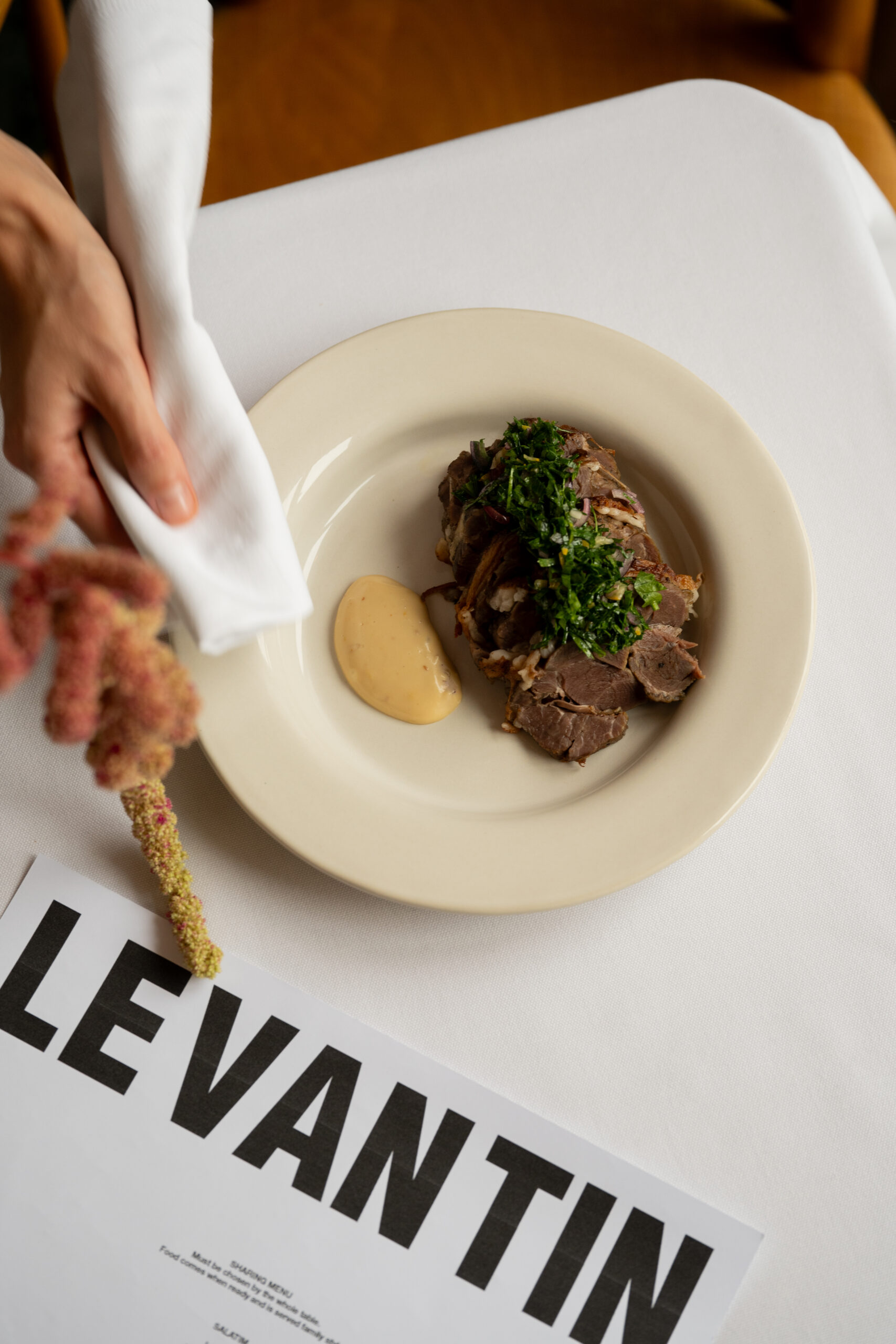 Image of a plate with barbecued lamb, garnish and sauce on the side