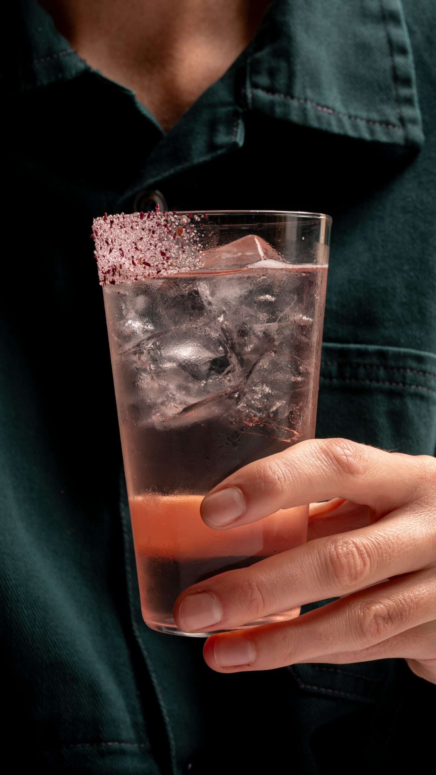 Close up of a hand holding a drink with ice and beautiful decorations on glass